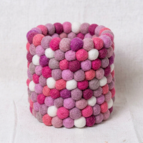 Empty cylindrical pen holder covered in pink, mauve and white textured balls.