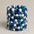 Empty cylindrical pen holder covered in blue, teal and white textured balls.